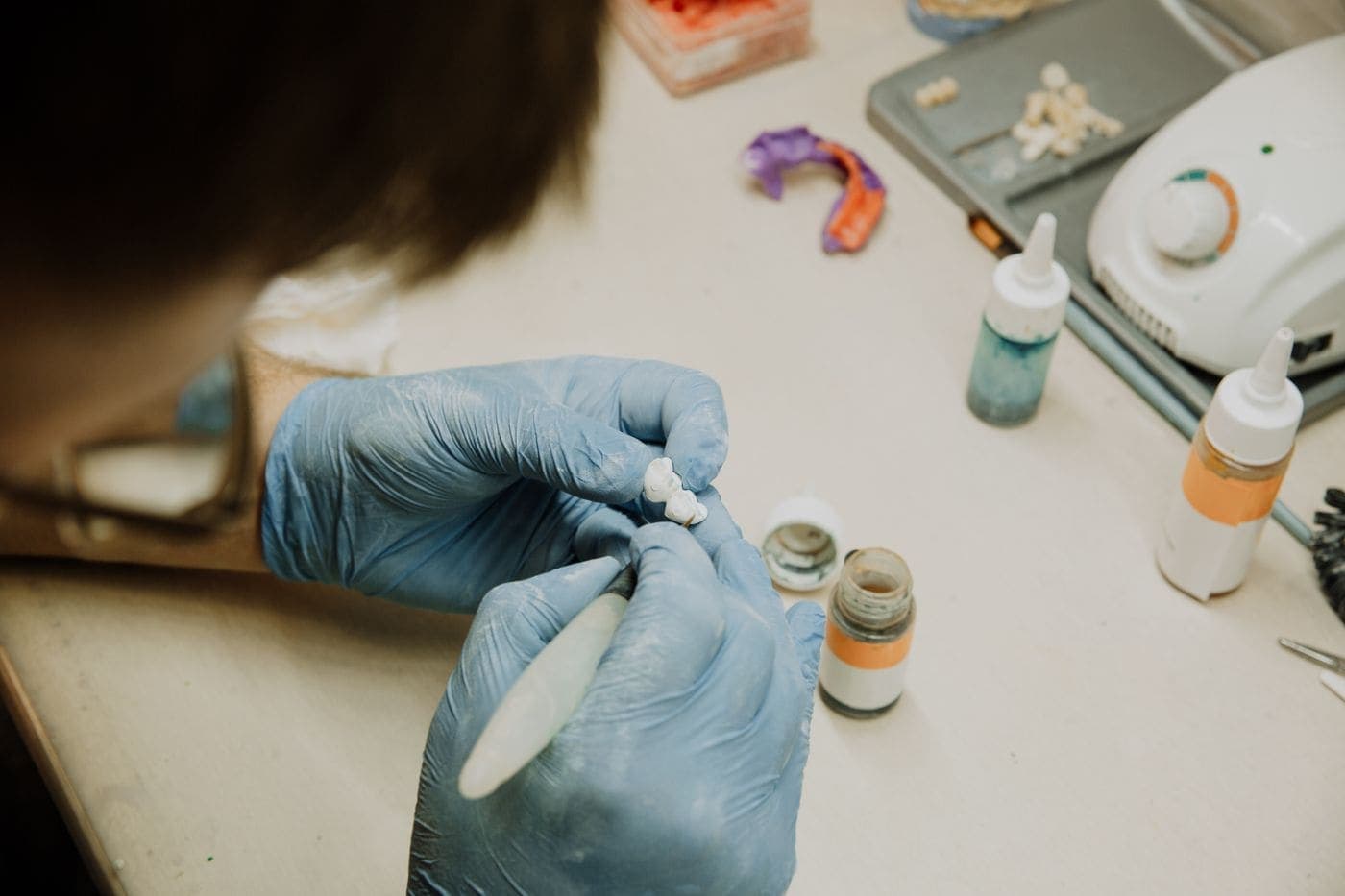 Dental ceramist hand-crafting a tooth restoration in the lab